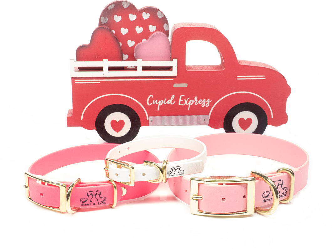 Red Cupid Express Truck with hearts in hearts in the background.  Hot Pink, Rose Pink and White Henry & Sadie Collars with Brass hardware shown in the foreground. 